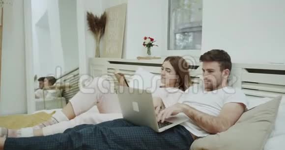 现代卧室在早上特写年轻女士在床上看书她的伴侣在床上看东西视频的预览图