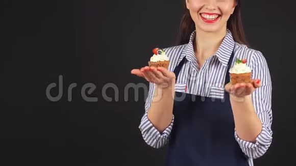 年轻女子手里拿着纸杯蛋糕的糕点师微笑着对着镜头视频的预览图