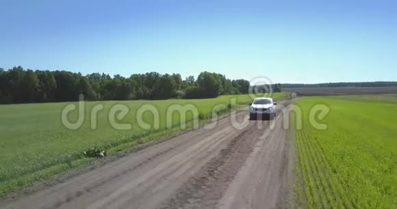 吉普车沿着灰色地面公路行驶驶向绿色的田野视频的预览图