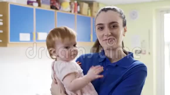 母亲把婴儿交给女婴儿保育员视频的预览图