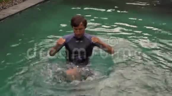 这个年轻人正在游泳池里训练他的格斗技巧在池中战斗训练的概念视频的预览图