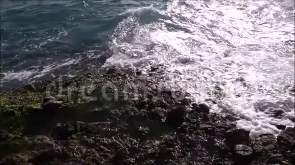 起伏的海水抚摸着岩石海岸视频的预览图