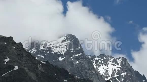 在阳光明媚的一天在旋转的积云背景下带有雪斑的尖尖陡峭岩石形成了特写镜头视频的预览图