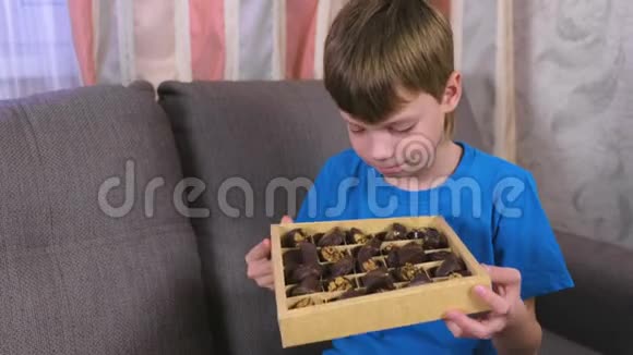 坐在沙发上的男孩在盒子里嗅巧克力视频的预览图
