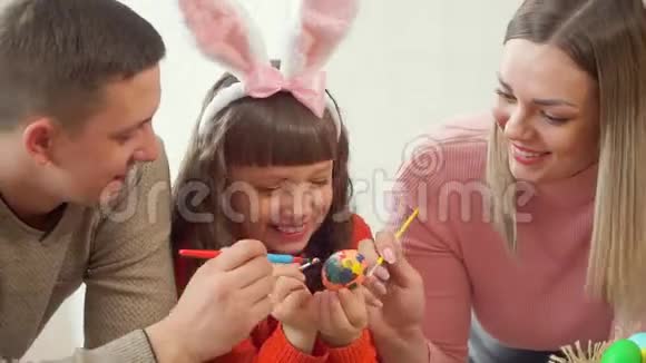 年轻幸福的家庭一起装饰一个复活节彩蛋里面有一个女儿视频的预览图