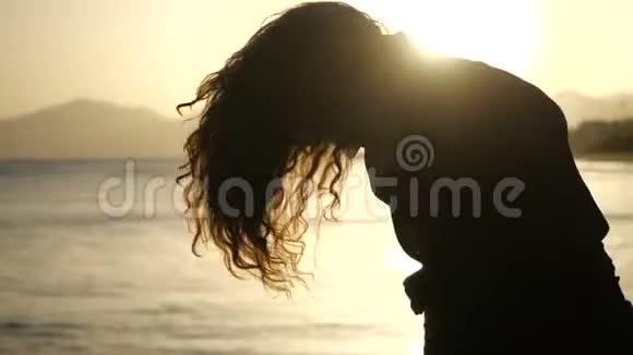 缓慢的动作结束了年轻女人移动她的头的轮廓头发在风中吹着看着大海上的日落视频的预览图