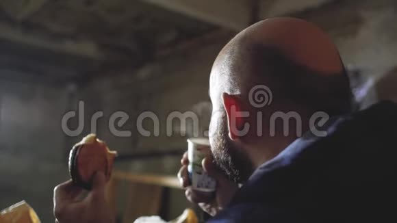 秃头的男人从一次性杯子里喝茶吃一个面包视频的预览图