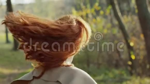 美丽的女孩挥舞着她的头红色的头发阳光灿烂的公园视频的预览图