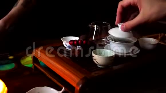 中国茶道拿起茶壶把热茶倒入装有陶瓷的玻璃罐子里视频的预览图