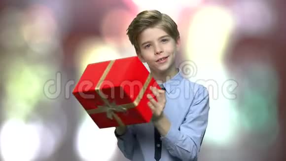可爱的孩子在模糊的背景上摇动礼盒视频的预览图