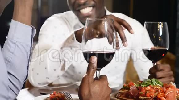 两个面目全非的非洲朋友坐在餐厅的桌子上喝着一杯酒非洲男性手拿着杯子视频的预览图