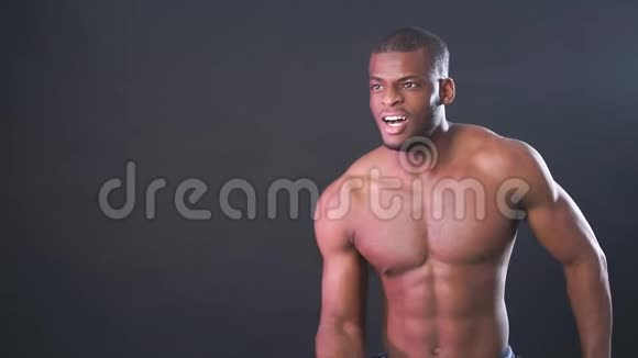 肌肉男非洲健美运动员男人在黑色背景上摆姿势展示他的健康和完美的形状视频的预览图