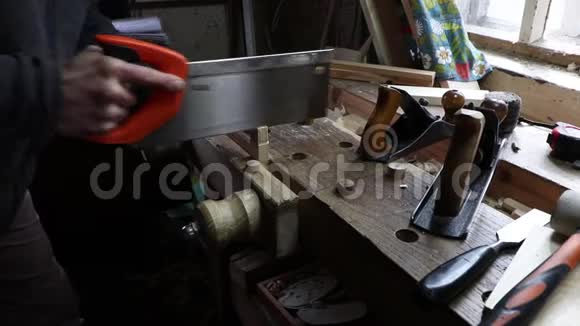 男工在棚子里的木工作台上用手锯切松木木板更高的角度在肩膀上视频的预览图
