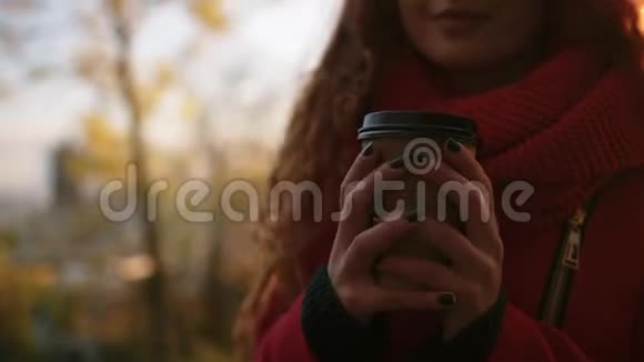 一个女孩站在公园的户外享受她的咖啡的美妙的幸福景象美丽的年轻女子长着红色视频的预览图