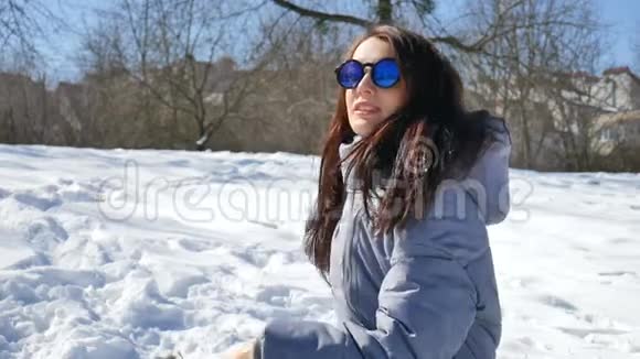漂亮的深色头发戴着蓝色镜面太阳镜直发扔雪球在户外和别人玩视频的预览图