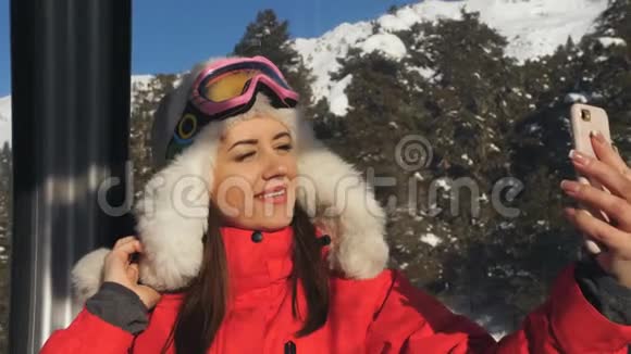 滑雪场女人在机舱滑雪电梯的智能手机上自拍视频的预览图