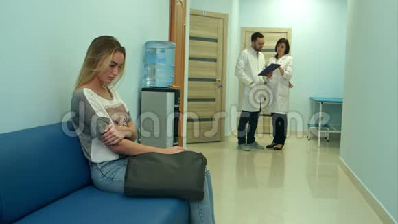 女病人在医院大厅等候两名医生在咨询视频的预览图