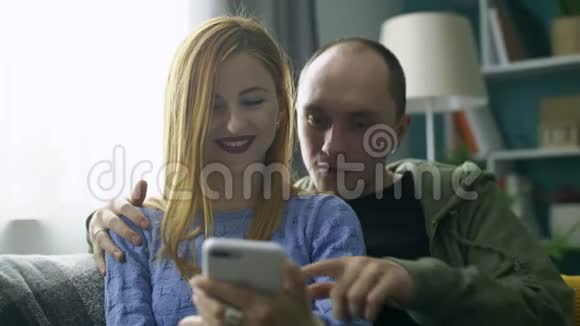 一对夫妇在客厅的沙发上用智能手机视频的预览图