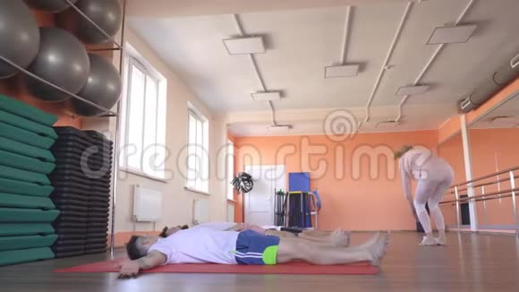 高加索女教师进行瑜伽课程沙瓦萨纳姿势男性朋友说谎和放松恢复和更新视频的预览图