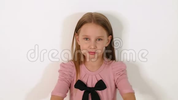 一个穿着粉红色连衣裙的小女孩正站在工作室的白色墙壁上视频的预览图