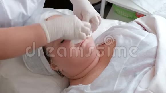 美容店洗脸的女性程序一位戴着白手套的美容师擦着女孩额头n视频的预览图