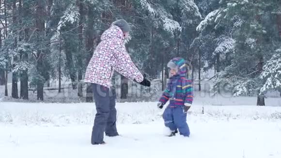一位快乐的母亲抱着她的儿子在一个美丽的冬日里在森林或公园里亲吻他视频的预览图