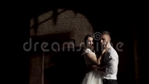 漂亮的新婚夫妇站在黑色的墙上影子从金属门行动年轻新娘的肖像视频的预览图