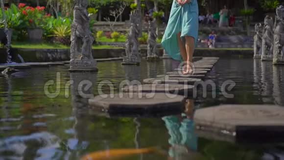 一位年轻的女游客参观巴厘岛前皇家宫殿提塔甘加水宫时的慢镜头视频的预览图