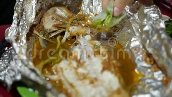 在亚洲街头食品市场游客吃春卷和用箔纸煮熟的鱼关门视频的预览图