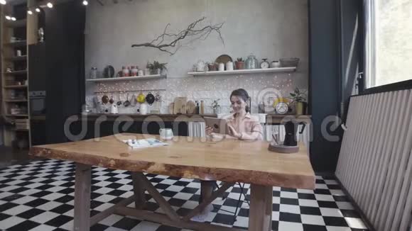 科技互联网和家庭概念女性在坐在木制漂亮的桌子前使用平板电脑视频的预览图