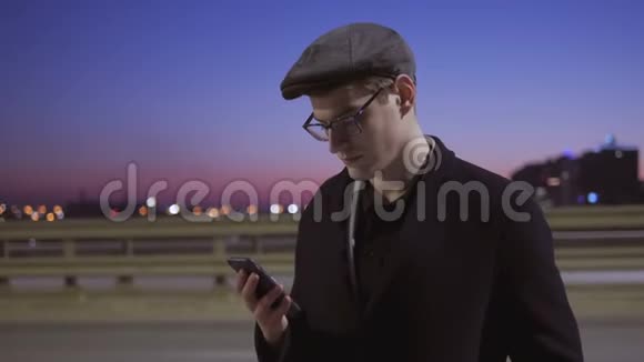 男人用手机一个人站在马路附近的街道上车经过视频的预览图