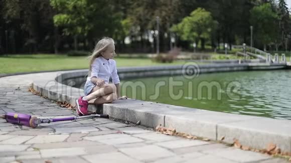 美丽的金发女孩在公园的湖边休息视频的预览图
