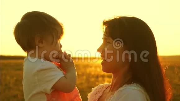 妈妈和一个小女儿说话孩子坐在母亲的怀里春天幸福的一家人在公园散步视频的预览图