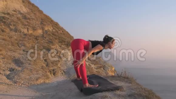 美丽的景色女人做瑜伽Dvikonasana双三角软管在山上日落时的海景视频的预览图
