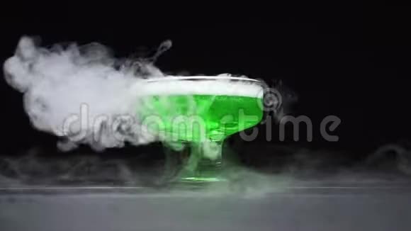 绿色液体沸腾在黑色背景下的玻璃碗中散发烟雾视频的预览图