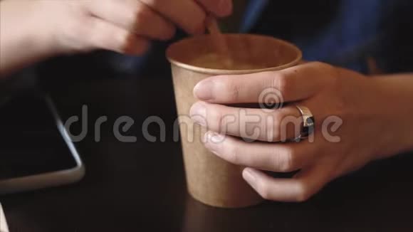 年轻的素食女孩用咖啡在纸杯中搅拌糖或甜叶菊视频的预览图