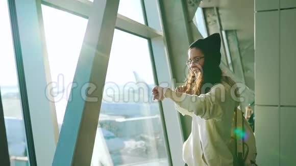 旅行女孩站在机场候机楼的窗口视频的预览图