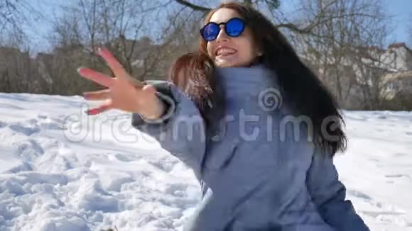 穿着蓝色镜子太阳镜直发扔雪球在户外玩耍和欢笑的成年女孩微笑视频的预览图