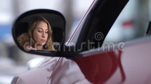 车里漂亮的女孩用粉红色的口红涂嘴唇侧镜反射4K慢莫视频的预览图