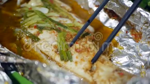 游客在亚洲街头食品市场用筷子煮鱼特写视频的预览图