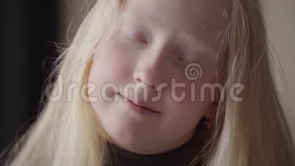特写一个白化病女孩的肖像灰色的眼睛看着相机微笑不寻常的外表免费儿童视频的预览图