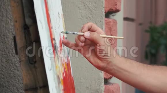 特写艺术家手握画笔画在街头画布上慢动作视频的预览图
