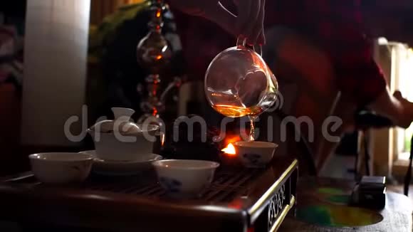 中国茶道拿起茶壶把热茶倒入装有陶瓷的玻璃罐子里视频的预览图