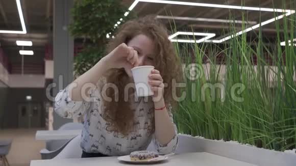 年轻漂亮的红发女人坐在咖啡馆里吃咖啡里的棉花糖视频的预览图