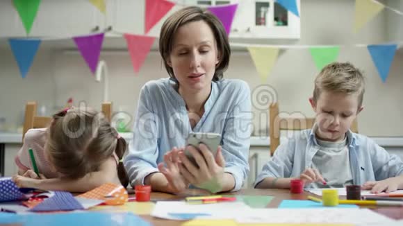 母亲和她的孩子坐在一起孩子们在做节日的工艺品微笑着视频的预览图
