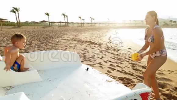 日落时快乐的小男孩和他的母亲在海边玩的4k视频暑假玩得很开心视频的预览图
