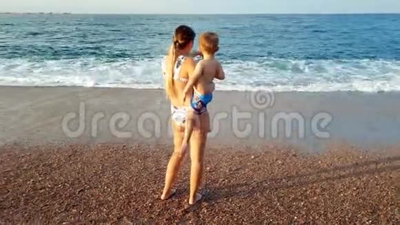 4k视频日落时分年轻女子在沙滩上拥抱她的孩子视频的预览图