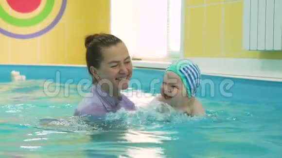 婴儿和游泳教练在游泳池里玩得开心视频的预览图
