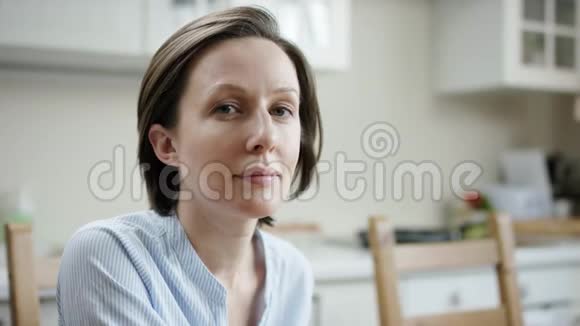 女人坐在厨房里看着然后微笑视频的预览图