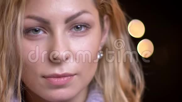 一位成年金发白种人女性在镜头前直视镜头背景是bokeh灯视频的预览图